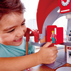 ילד משחק במשחק רכבת של HAPE, משחק רכבת שכולל גם דמויות בתחנה
